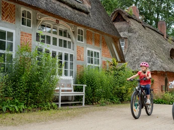 Zwei Mädchen fahren Fahrrad beim Haus im SchluhTwo girls riding bicycles near the house in the SchluhTo piger cykler nær huset i Schluh.Twee meisjes fietsen bij het huis in de Schluh