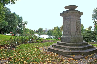 Mahnmal Weserwall Steinmonument am Weserwall, umgeben von Herbstlaub und Bäumen in einer friedlichen Parklandschaft.