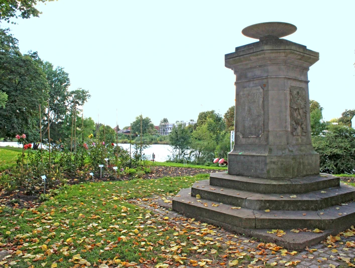 Mahnmal Weserwall Steinmonument am Weserwall, umgeben von Herbstlaub und Bäumen in einer friedlichen Parklandschaft.