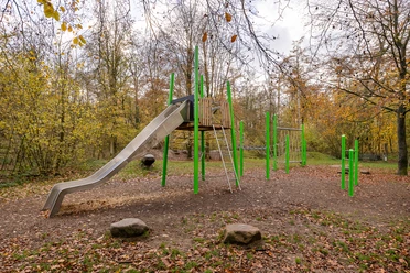 Kinderspielplatz am Wanderparkplatz Hinkesforst in Ratingen Ein moderner Spielplatz mit Rutsche und Klettergerüst, umgeben von herbstlichen Bäumen im Hinkesforst.