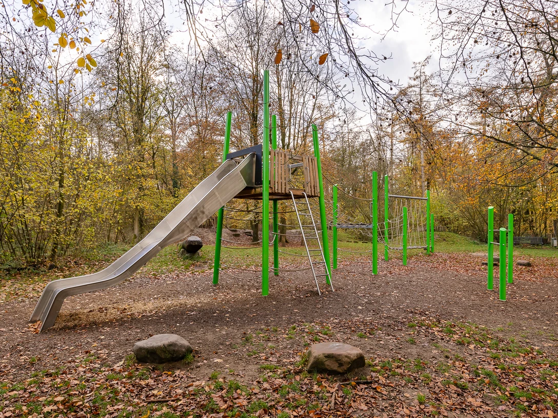 Kinderspielplatz am Wanderparkplatz Hinkesforst in Ratingen Ein moderner Spielplatz mit Rutsche und Klettergerüst, umgeben von herbstlichen Bäumen im Hinkesforst.