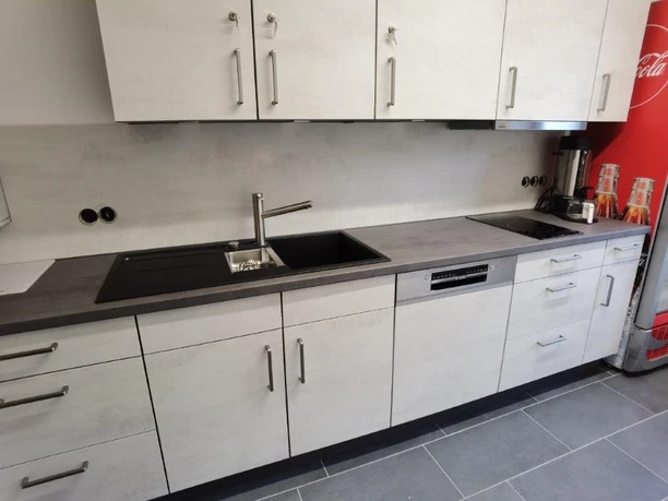 Küche Moderne Küchenzeile mit Spüle, Herd und Kühlschrank, helles Design, rote Details rechts im Bild.