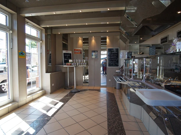 Innenraum-total Heller Innenraum des Bistros mit Theke, Stehtischen und großen Fenstern.