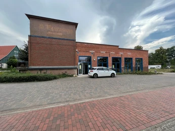 Backsteingebäude des Druckereimuseums in Hoya, ein Auto parkt davor, umgeben von gepflastertem Gelände.