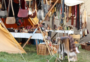 Mittelalterlicher Händler Marktstand mit mittelalterlichen Waren wie Ledertaschen, Fellkleidung, Holzgeschirr und Körben.