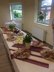 Seniorenfrühstück Ein langer Frühstückstisch mit Wurstplatten, Käse und frischen Kräutern auf weißen Tischdecken.
