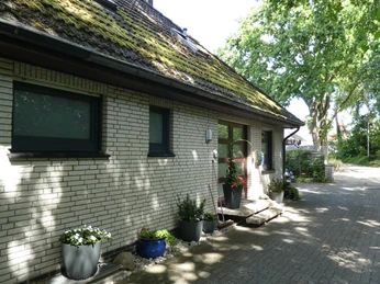 Radler-Pension Bormann Ein mit Efeu bewachsenes, graues Ziegelgebäude mit gepflegten Pflanzkübeln und schattenspendenden Bäumen.