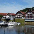 Ein Hotel-Restaurant mit roten Backsteinwänden am Ufer, umgeben von Booten am ruhigen Wasser.