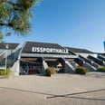 Eissporthalle Ratingen Große Eissporthalle in Ratingen mit markantem Dach, umgeben von Pflanzen und einem gepflasterten Vorplatz.