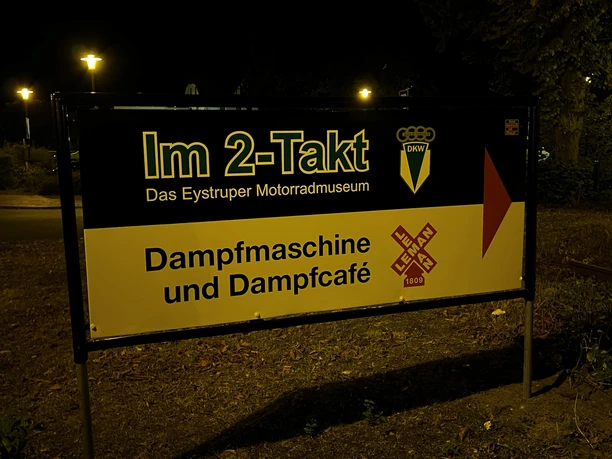 Schild Illuminated sign of the Eystrup Motorcycle Museum with reference to the steam engine and steam caé.