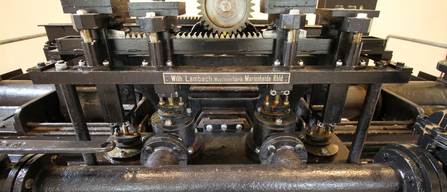 Lambach Pumpe Antiker mechanischer Webstuhl in Nahaufnahme, mit Zahnrädern und Hebeln aus schwarzem Metall.