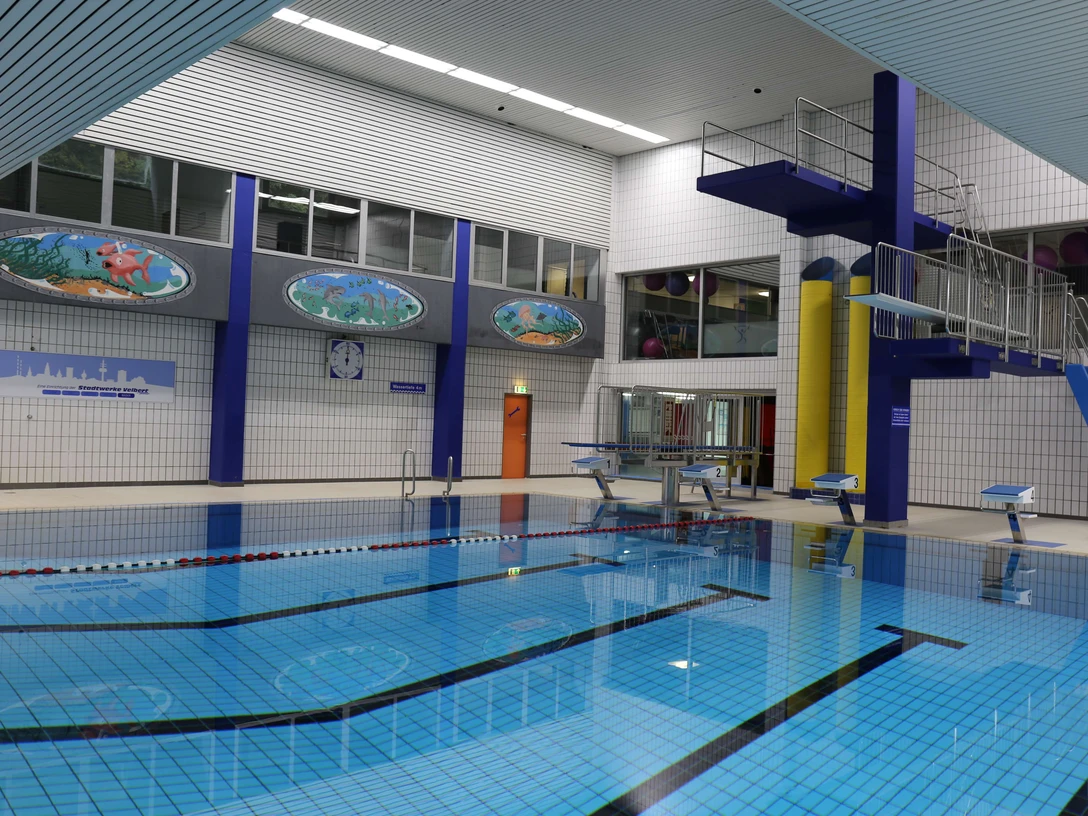 Nizzabad bei Velbert-Langenberg Ein modernes Hallenbad mit klar strukturiertem Becken, Leitern, Sprungturm und farbenfrohen Wandbildern.