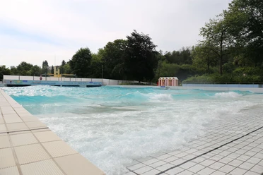 Panoramabad in Velbert Ein weitläufiges Freibad in Velbert mit türkisfarbenem Wasser und umliegendem Grün.