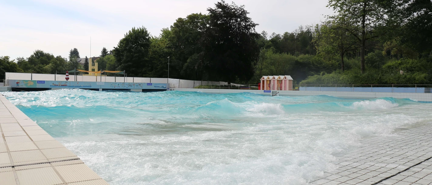 Panoramabad in Velbert Ein weitläufiges Freibad in Velbert mit türkisfarbenem Wasser und umliegendem Grün.