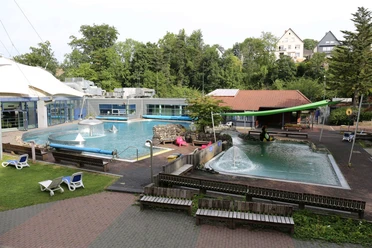 Parkbad in Velbert Ein Freibad mit zwei Pools und Sprungturm, umgeben von Bäumen und Liegestühlen in Velbert.