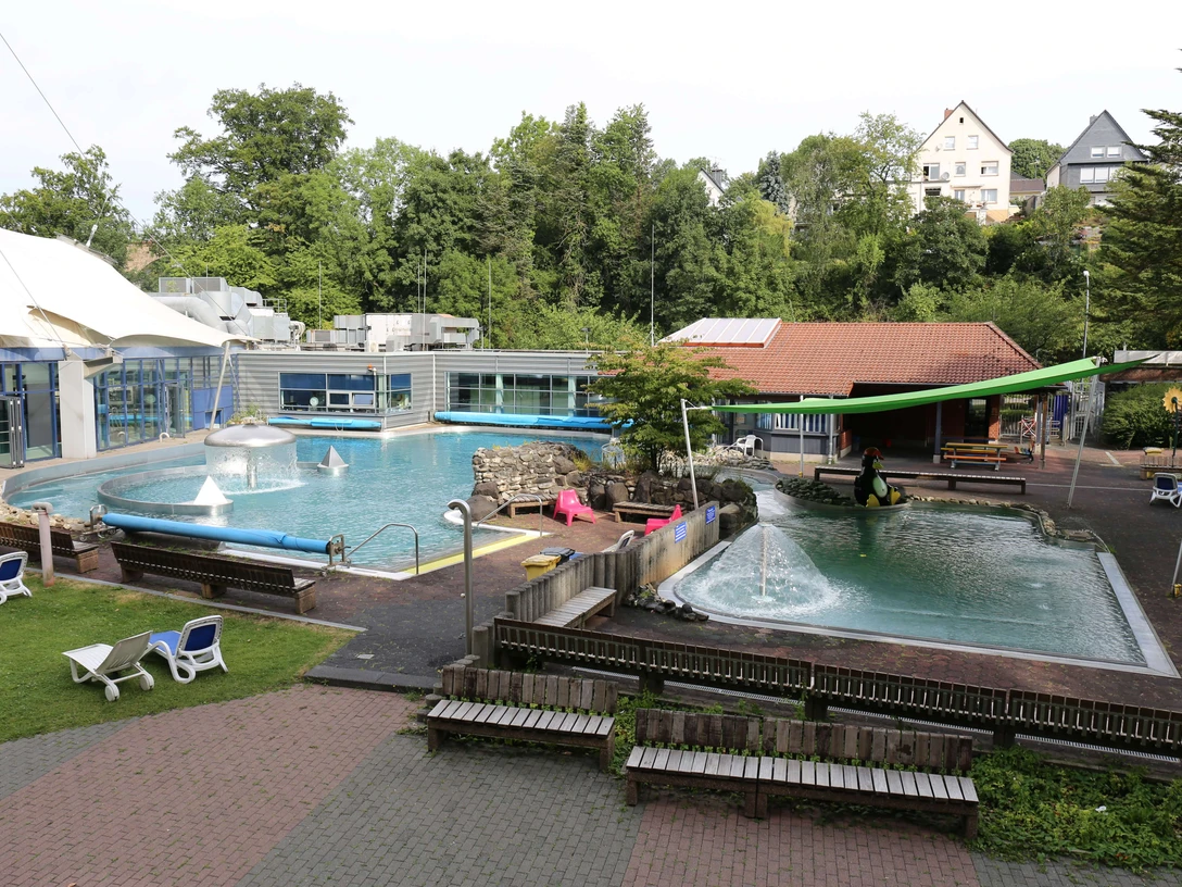 Parkbad in Velbert Ein Freibad mit zwei Pools und Sprungturm, umgeben von Bäumen und Liegestühlen in Velbert.