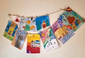 Malzauber-Malkurse Kreative Kinderzeichnungen an einer Schnur aufgehängt, präsentieren bunte Tiere und fantasievolle Szenen.