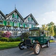Lohmanns Romantik Hotel Gravenberg in Langenfeld Historisches Hotel mit grünen Fensterläden und Oldtimer im Vordergrund, umgeben von Landschaft.