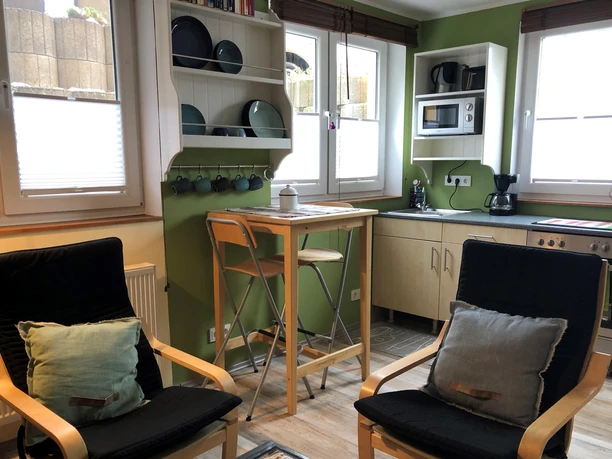 Appartments Am Kaldenberg in Mettmann Heller, moderner Küchenbereich in einem Apartment mit grünen Wänden, Holzmöbeln und Sitzgelegenheiten.