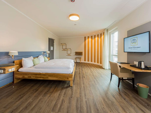 Hotel Neues Pastorat in Heiligenhaus Modernes Hotelzimmer im Neuen Pastorat, Heiligenhaus, mit Holzfußboden und stilvoller Einrichtung.