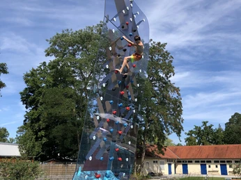 Waldfreibad Espelkamp Ein Junge klettert an einer durchsichtigen Kletterwand über einem Schwimmbecken im Waldfreibad Espelkamp.