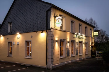Außenansicht der Krone Homberg in Ratingen Außenansicht des Gebäudes Krone Homberg in Ratingen bei Abenddämmerung, beleuchtet und einladend.