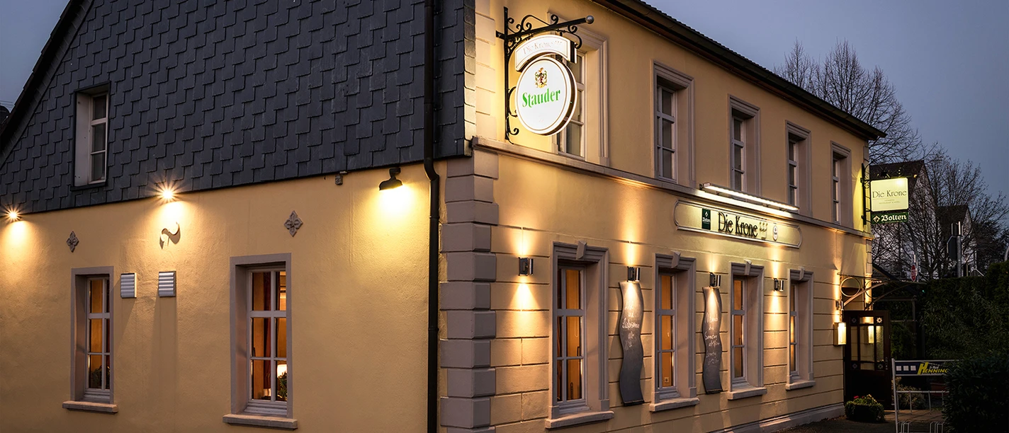 Außenansicht der Krone Homberg in Ratingen Außenansicht des Gebäudes Krone Homberg in Ratingen bei Abenddämmerung, beleuchtet und einladend.