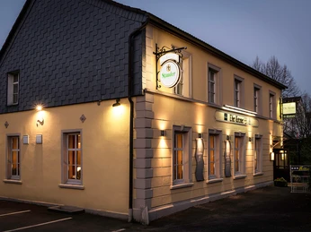 Außenansicht der Krone Homberg in Ratingen Außenansicht des Gebäudes Krone Homberg in Ratingen bei Abenddämmerung, beleuchtet und einladend.