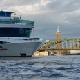 Köln-Düsseldorfer Deutsche Rheinschiffahrt Ein modernes Flusskreuzfahrtschiff der Köln-Düsseldorfer passiert malerisch die Rheinbrücke mit ihrem prägnanten Bogen und den angrenzenden, markanten Bauten im Hintergrund.A modern river cruise ship operated by Köln-Düsseldorfer passes picturesquely over the Rhine bridge with its striking arch and the adjacent, striking buildings in the background.