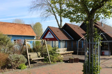 Seglertreff Otterndorf Einladender Imbiss Seglertreff Otterndorf mit Holzterrasse und Schaukel unter Bäumen.