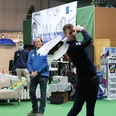 Indoorgolf bei Team Spieckerhoff in Langenfeld Personen spielen in einer Indoor-Golfanlage. Einer schwingt gerade den Schläger, im Hintergrund Golfzubehör.