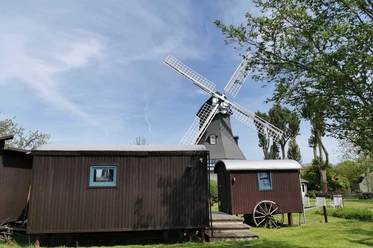 Traumwagen an der Mühle Juliane Holzwagen vor großer Windmühle im Grünen