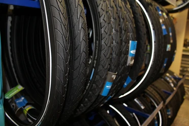 Fahrradzubehör Verschiedene Fahrradreifen hängen dicht beieinander im Regal eines Fachgeschäfts für Fahrradzubehör.