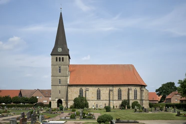 Elisabethkirche Die Elisabethkirche steht mit ihrem spitzen Turm auf einem gepflegten Friedhof unter blauem Himmel.