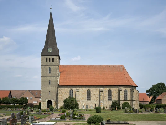 Elisabethkirche Die Elisabethkirche steht mit ihrem spitzen Turm auf einem gepflegten Friedhof unter blauem Himmel.