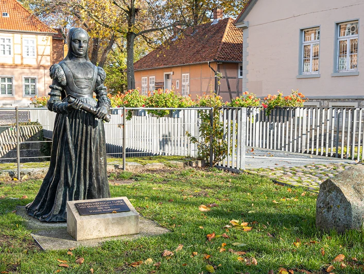 Schloss Fallersleben Bronzestatue einer Herzogin im Garten von Schloss Fallersleben vor Fachwerk- und Putzbauten.