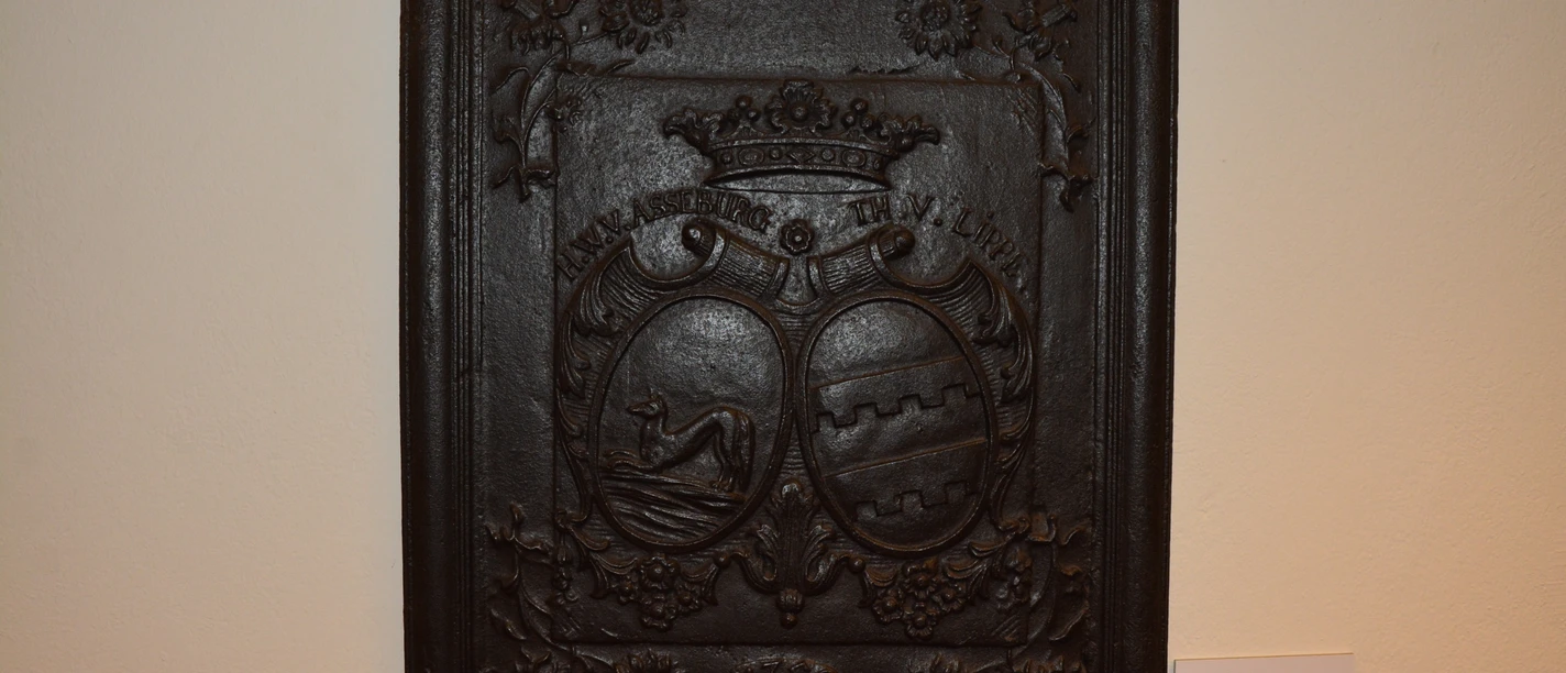 Wappenrelief aus schwarzem Metall mit filigranen Details, zwei Wappenmotiven und floralen Verzierungen.