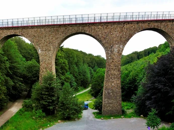 Eulenbachbrücke "Saubrücke" in Velbert auf dem PanoramaRadweg niederbergbahn Historische Bogenbrücke mit drei Öffnungen, umgeben von dichtem grünen Wald, führt über einen Radweg.