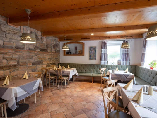 Da Giovanni Farchant - Innenbereich Gemütlich eingerichtete Stube mit großer Eckbank ringsherum und gedeckten Tischen