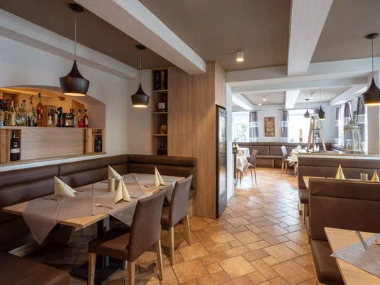 Da Giovanni Farchant - Innenbereich 2 Innenbereich mit braunen Ledereckbänken und Stühlen und einem Regal mit Wein- und Spirituosenflaschen