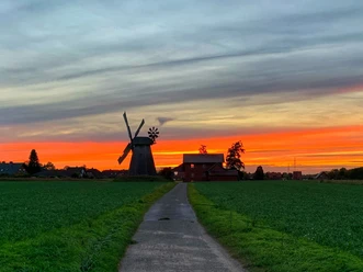 Windmühle Bierde Historische Windmühle in Bierde vor spektakulärem Sonnenuntergangshimmel in ländlicher Umgebung.
