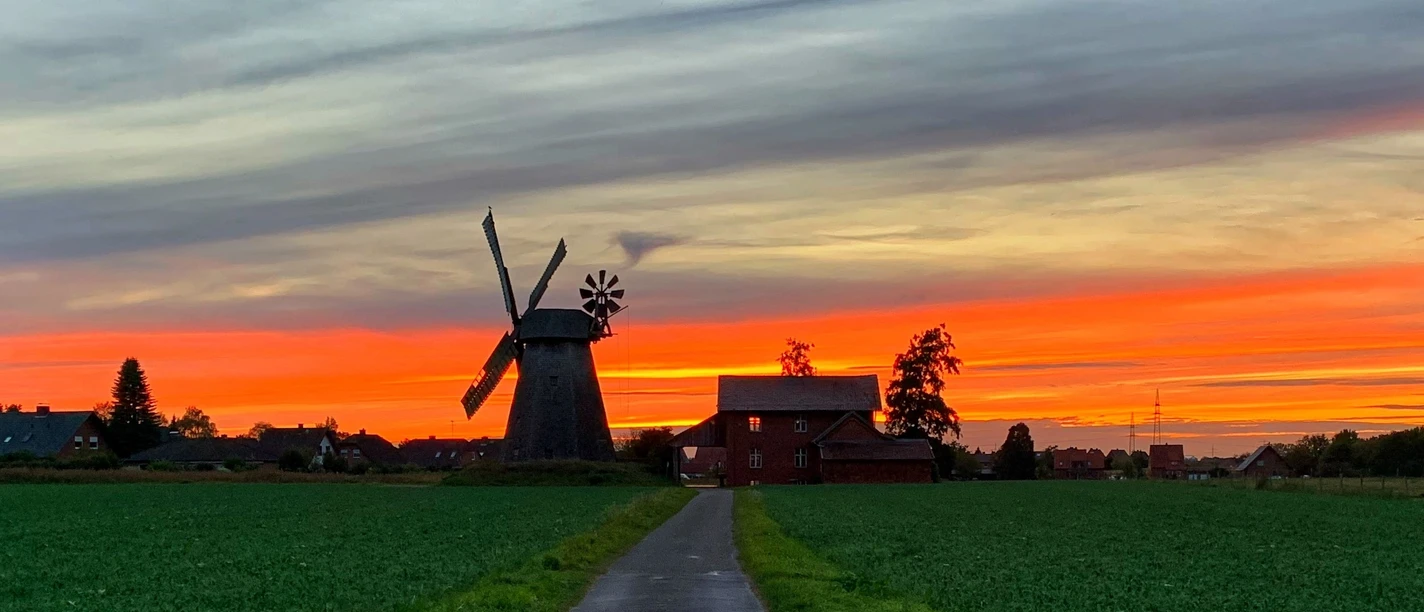 Windmühle Bierde Historische Windmühle in Bierde vor spektakulärem Sonnenuntergangshimmel in ländlicher Umgebung.