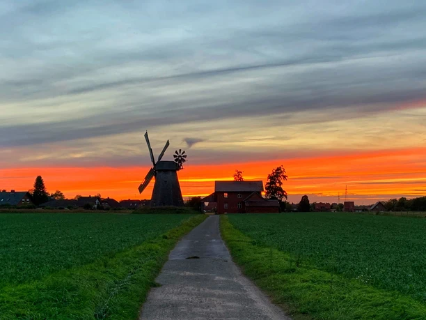 Windmühle Bierde Historische Windmühle in Bierde vor spektakulärem Sonnenuntergangshimmel in ländlicher Umgebung.