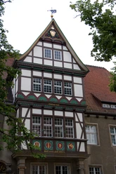 Fachwerkhaus mit Spitzgiebel, verziert mit kunstvollen Details und Wappen an der Fassade.