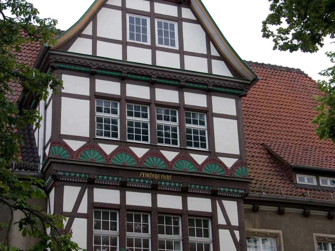 Fachwerkhaus mit Spitzgiebel, verziert mit kunstvollen Details und Wappen an der Fassade.