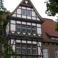 Fachwerkhaus mit Spitzgiebel, verziert mit kunstvollen Details und Wappen an der Fassade.
