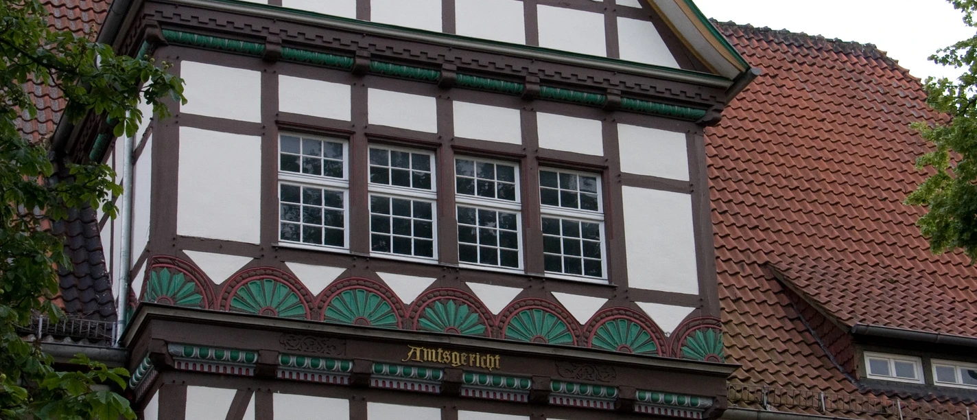 Fachwerkhaus mit Spitzgiebel, verziert mit kunstvollen Details und Wappen an der Fassade.