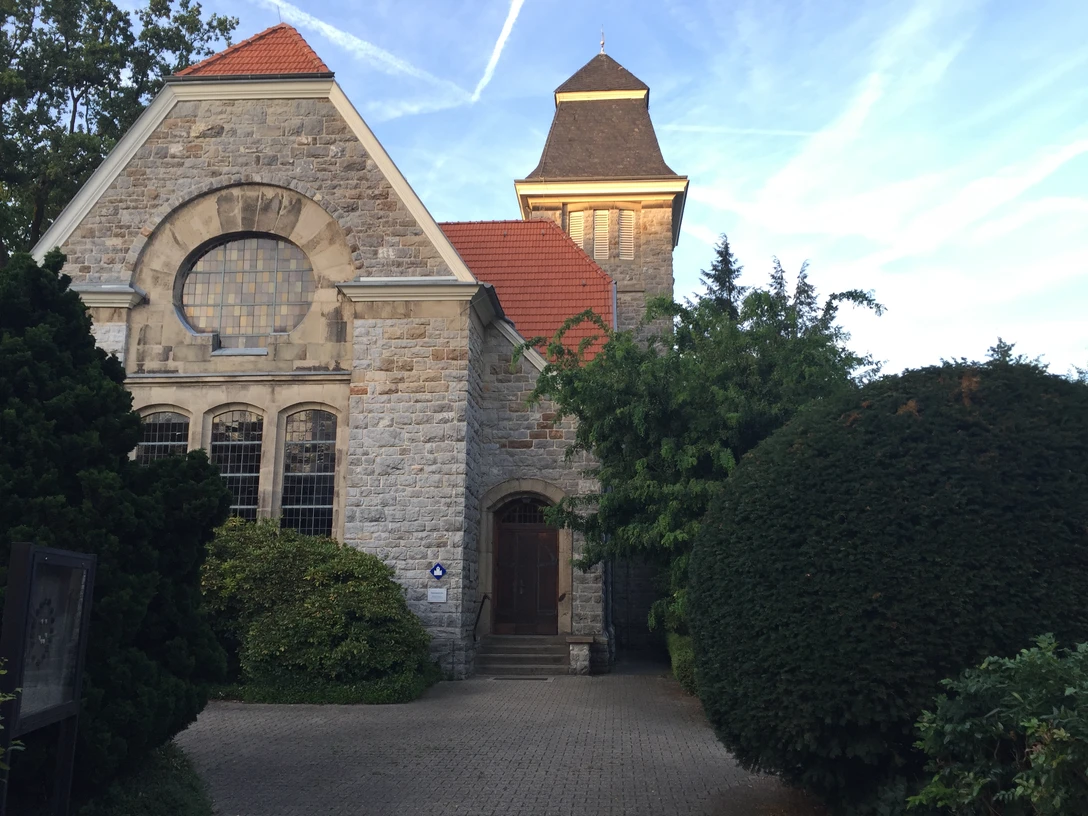 Neanderkirche in Erkrath Neanderkirche in Erkrath: Historische Backsteinkirche mit Turm, umgeben von grünen Pflanzen und Bäumen.