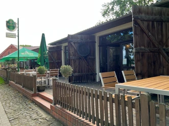 Cafe Weserscheune in Buchholz Hölzerne Terrasse des Cafés mit rustikalen Zäunen, Sonnenschirmen und Holzbänken im Freien.