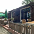 Cafe Weserscheune in Buchholz Hölzerne Terrasse des Cafés mit rustikalen Zäunen, Sonnenschirmen und Holzbänken im Freien.